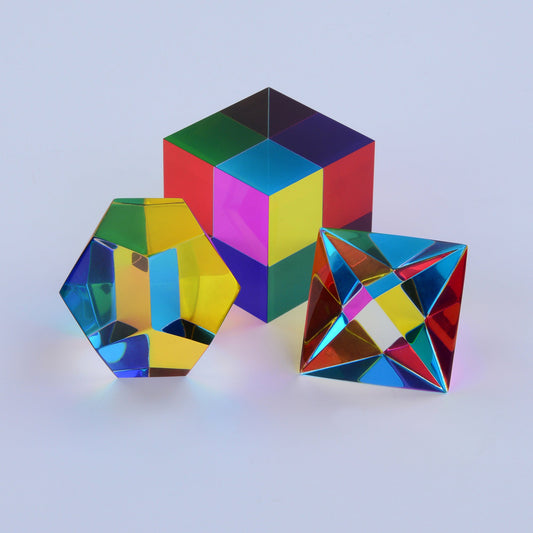 Three translucent CMY Platonic solids overlapping in sunlight, mixing cyan, magenta and yellow into new colours