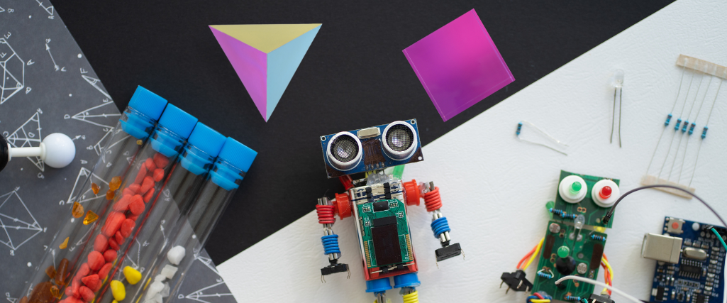 STEM kit with test tubes, a small robot, circuit boards and CMY shapes on a desk