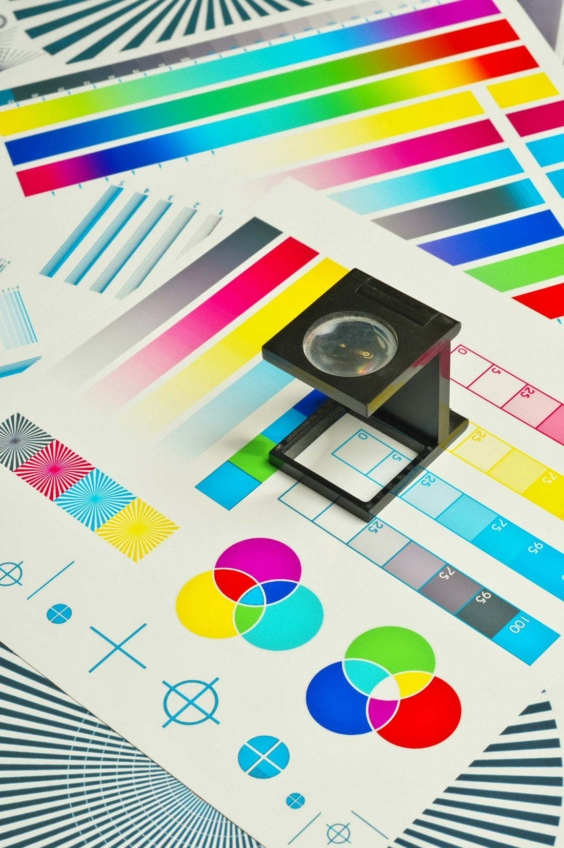 Magnifying loupe on a CMYK printing colour chart showing cyan, magenta, and yellow ink