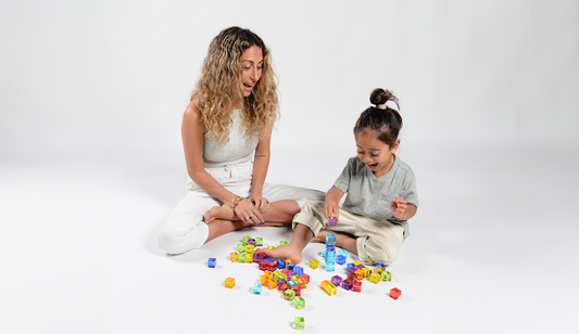Mother and toddler playing with colourful CMY shapes on the floor