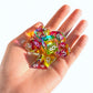 Seven translucent cyan, magenta, and yellow colour mixing dice cupped in an open palm